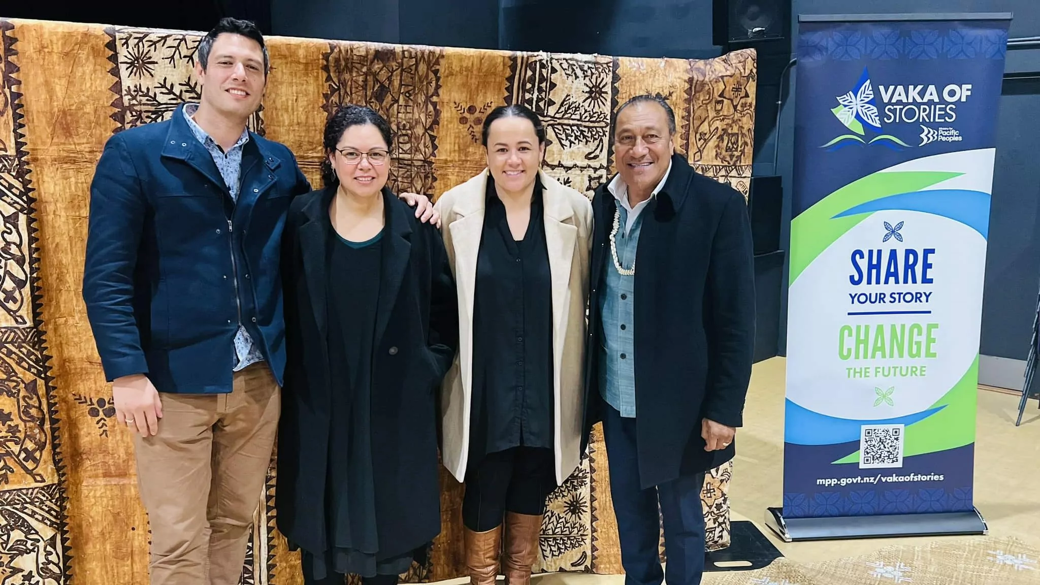 Four people in front of tapa cloth with Vaka of Stories banner.